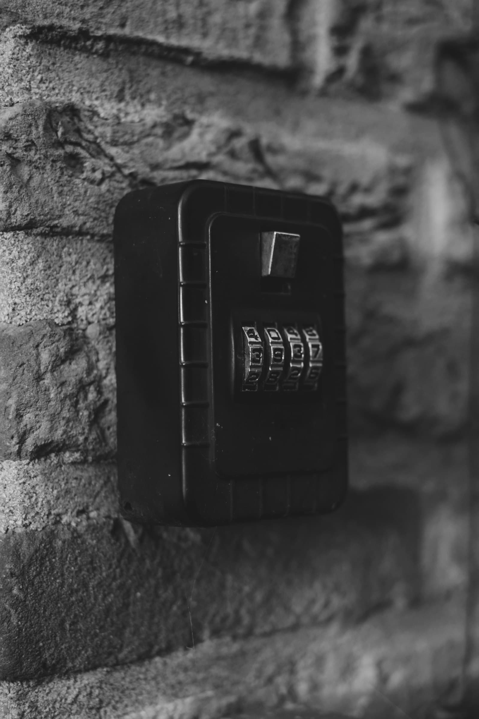Black combination lockbox with four-digit dial mounted on a brick wall — asset protection and security in Texas