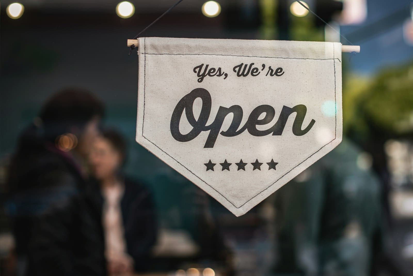Open sign hanging in a small business shop window with warm bokeh lights — entity formation in Texas