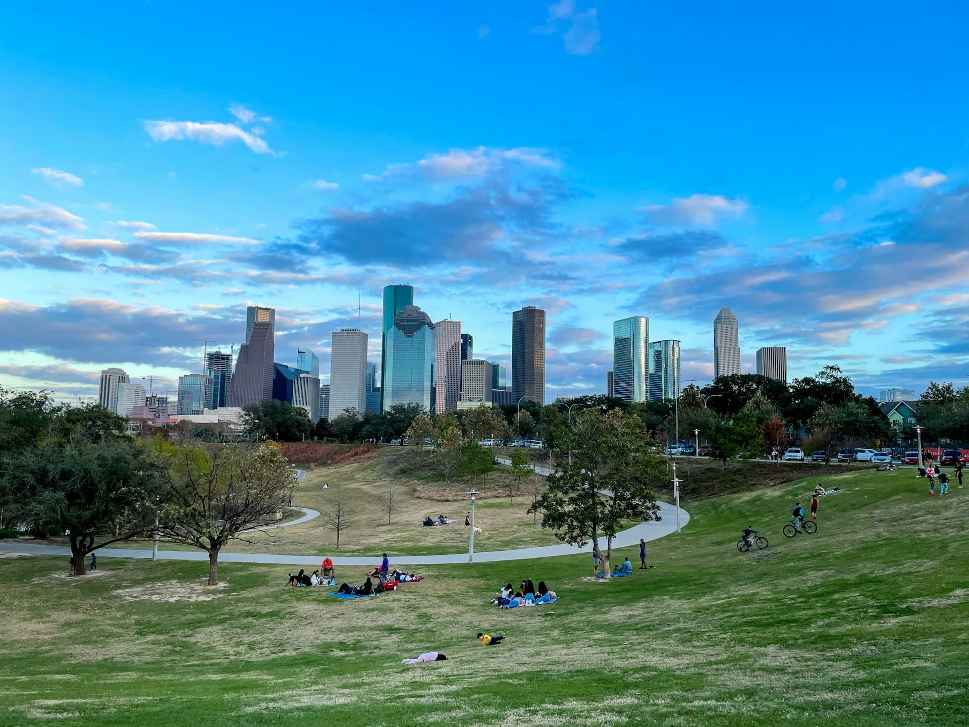 Houston skyline from Buffalo Bayou Park on a clear afternoon, people relaxing on the grass