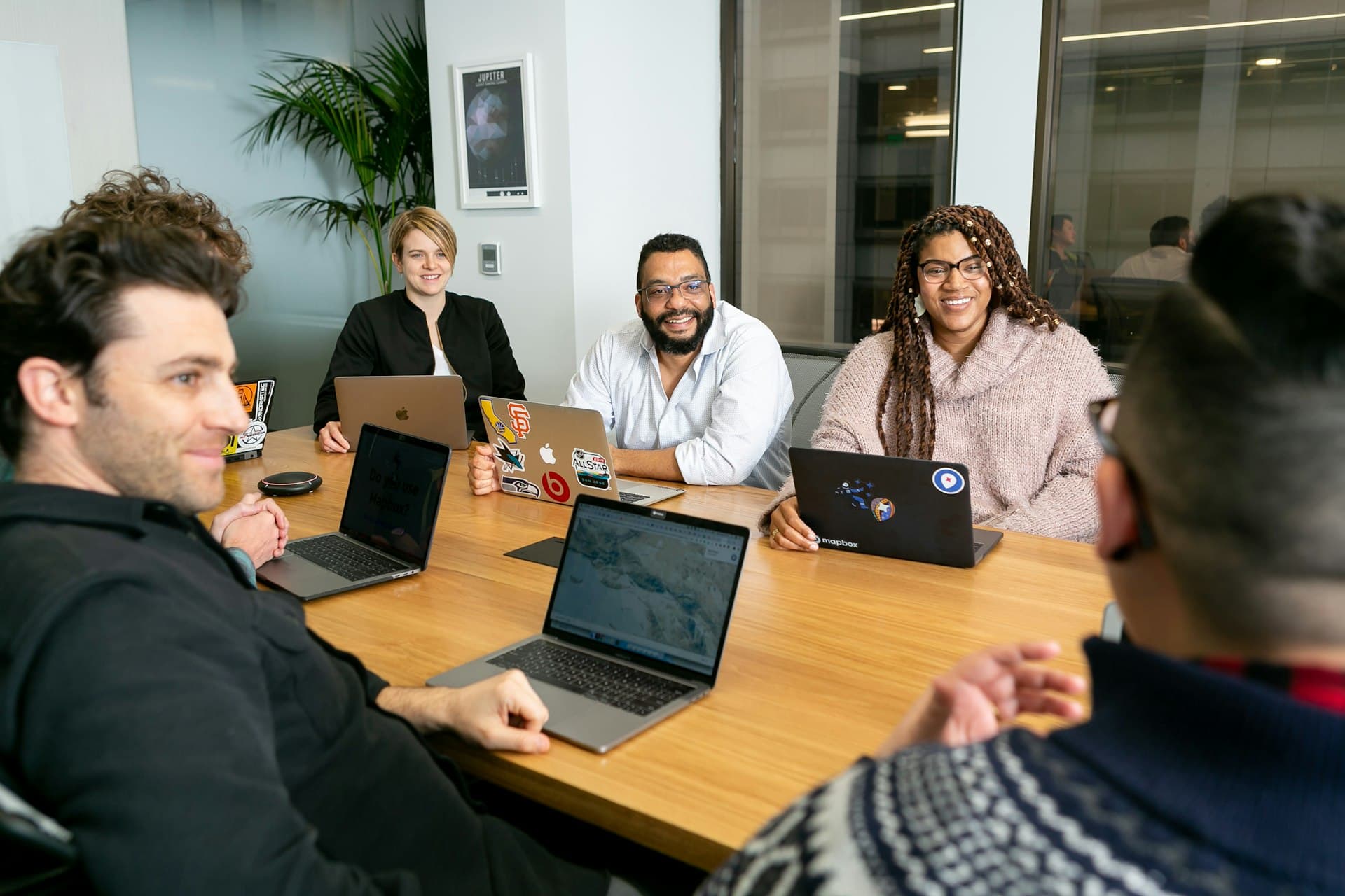 Five professionals working through plans together in a bright, casual office meeting room