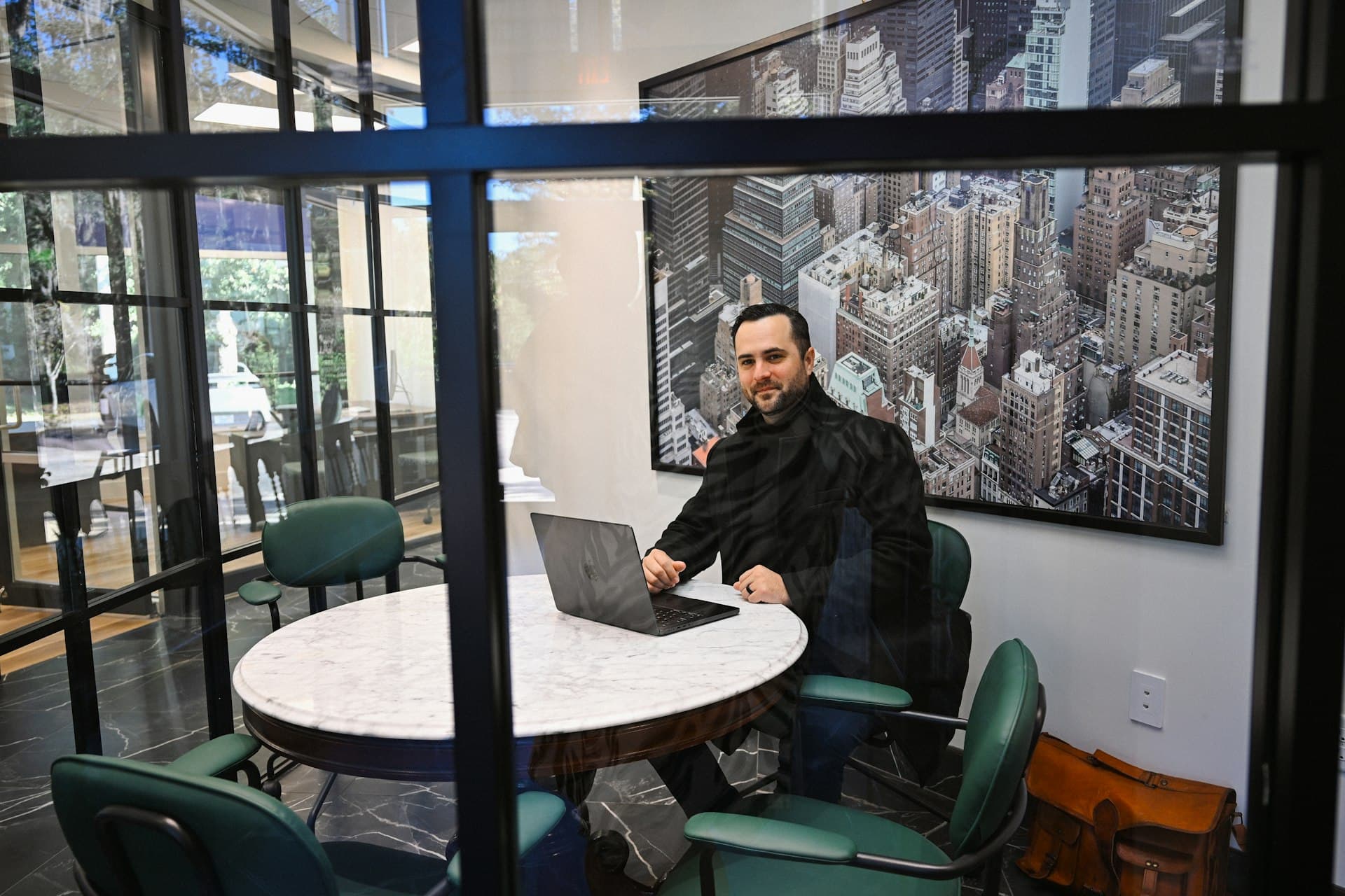 Attorney seated at a marble conference table in a glass office with a laptop open, showing what a consultation looks like