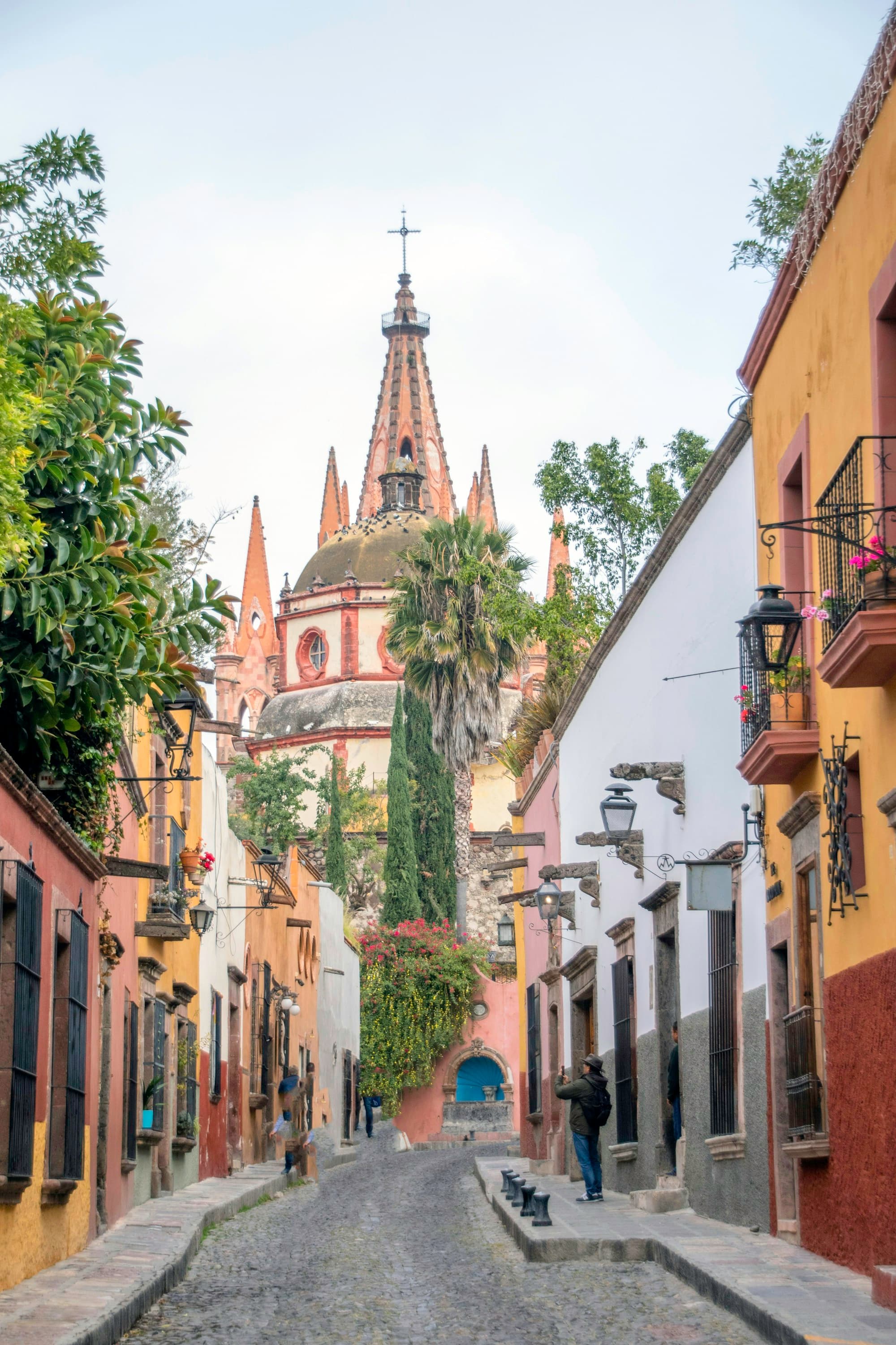 Cobbled street with colonial architecture and a parroquia spire in San Miguel de Allende